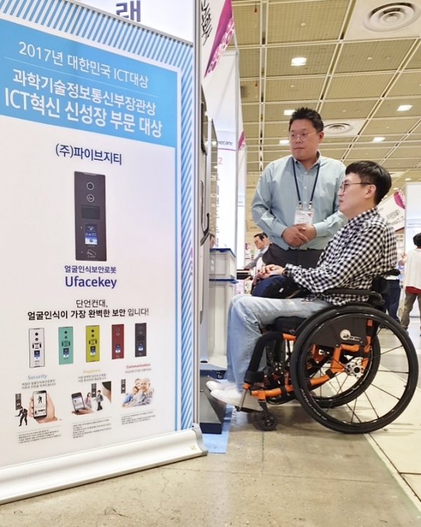 13일부터 15일까지 서울 코엑스에서 열리는 ‘2019 홈케어•재활•복지전시회(Reha.Homecare 2019)’에 참가한 파이브지티가 얼굴인식 보안로봇 ‘유페이스키(Ufacekey)’의 기능을 장애우에게 소개하고 있다.