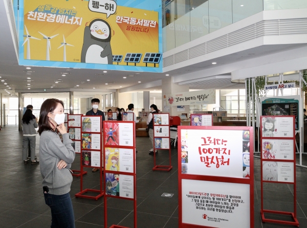 한국동서발전 직원들이 아동학대 예방을 위한 말상처 전시를 관람하고 있다.