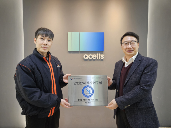 한화큐셀 박정필 시스템개발센터장(오른쪽)과 정상민 제품개발팀장이 서울 금천구 시스템개발센터에서 ‘안전관리 우수연구실’ 인증패를 들고 기념 촬영을 하고 있다.
